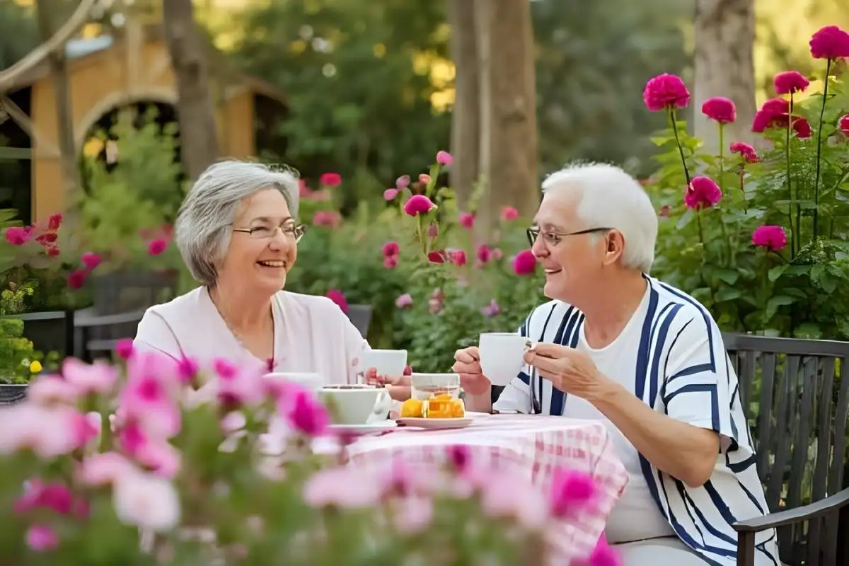 Happy seniors enjoying tea near their blooming garden